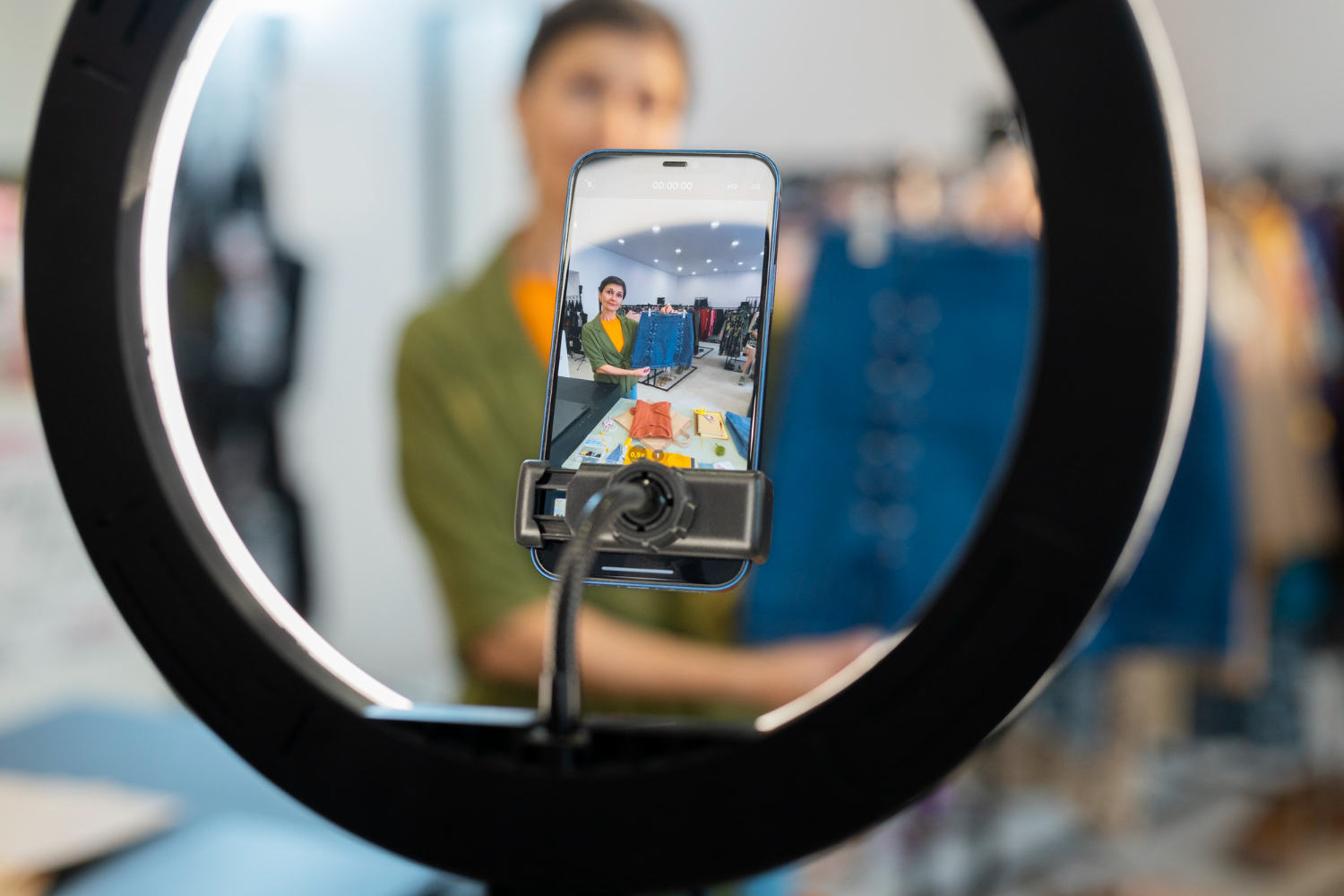 A woman broadcasts from a phone on a tripod